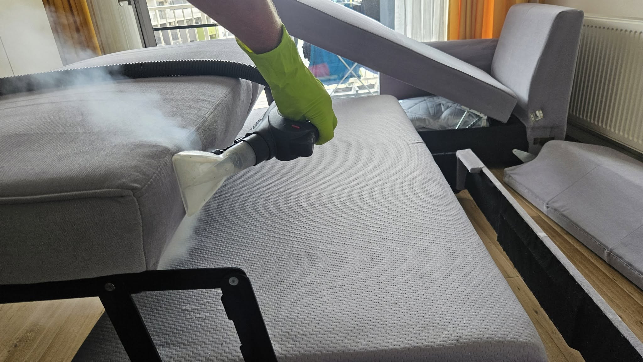 Curățare profesională a unei canapele extensibile gri cu echipament de extracție, la domiciliu în Oradea.